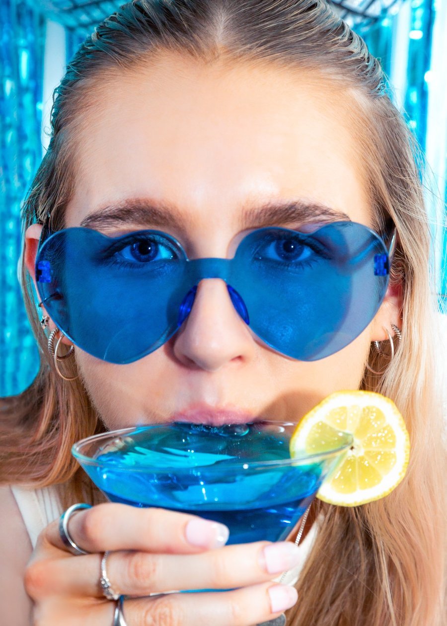 Guest in blue heart sunglasses sipping a disco cocktail