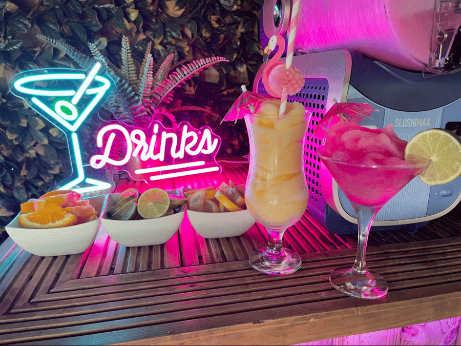 Two frozen cocktails with tropical garnishes on the bar
